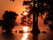 Bright orange and red sunset with trees in the river